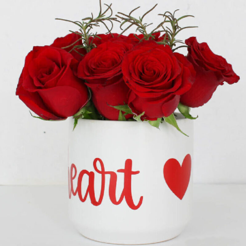 red roses in a white vase with a heart sticker