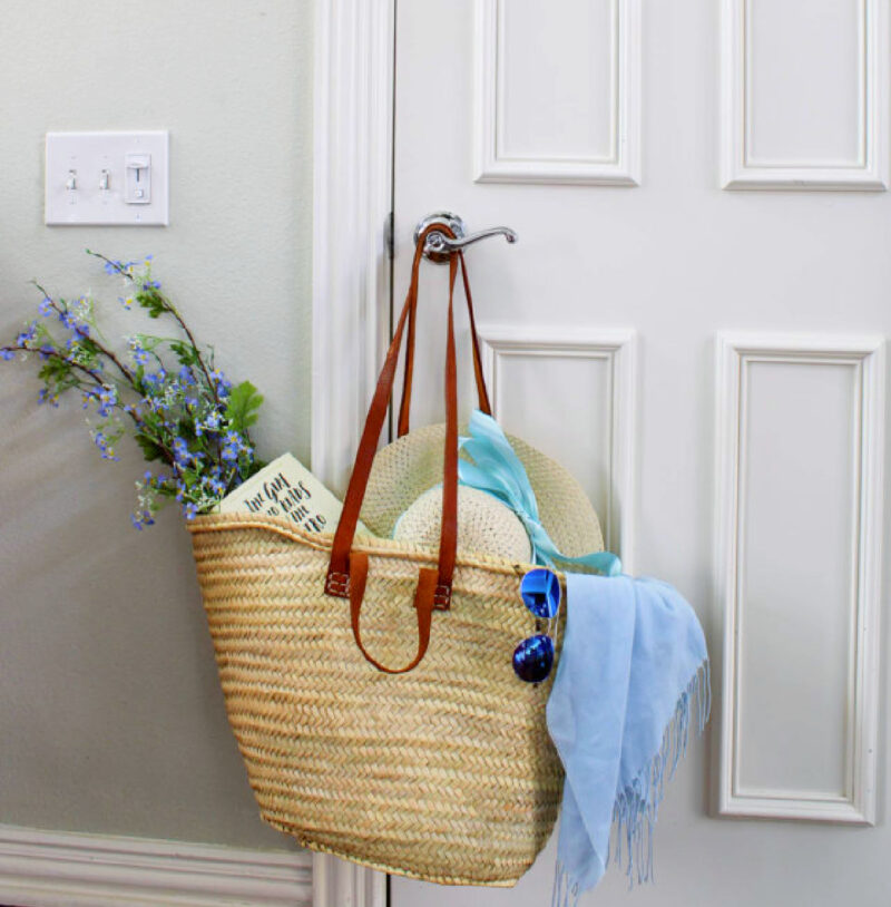 idea for decorating basket French market basket with flowers, book, blue shawl, and blue sunglasses
