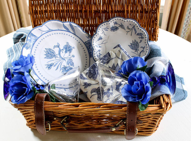 idea for decorating basket brown picnic basket with blue and white plates and napkins and blue flowers