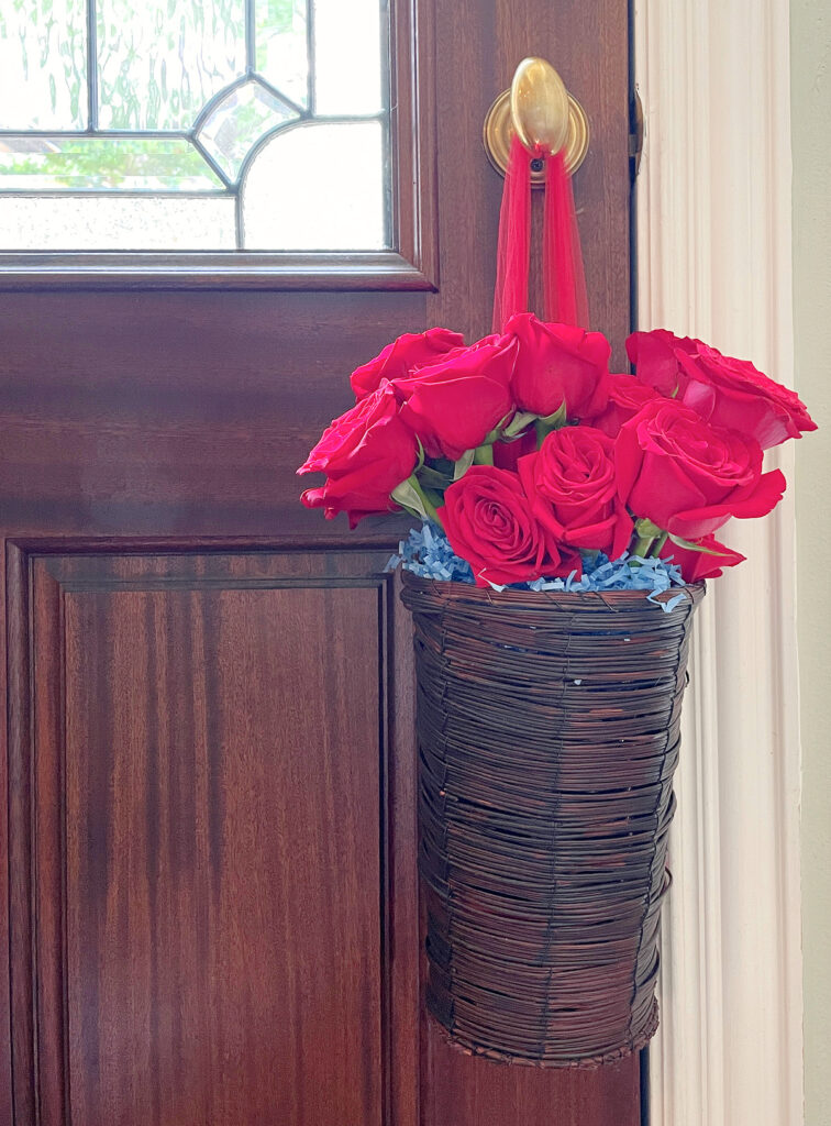 Ideas for Decorating Baskets hanging on door knob with red netting filled with red roses and blue shredded paper