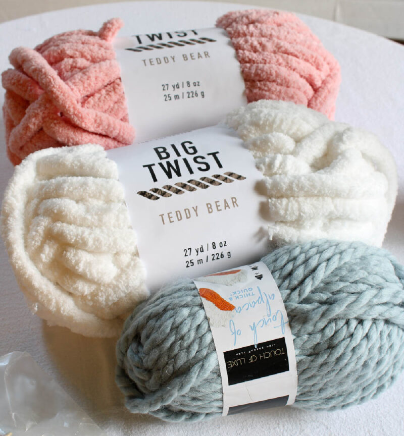 three steins of yarn in pink, white, and blue