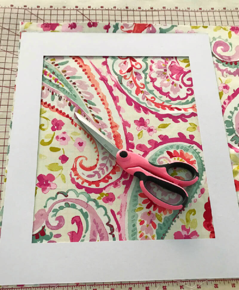 bright colored paisley pattern fabric in gold frame with scissors