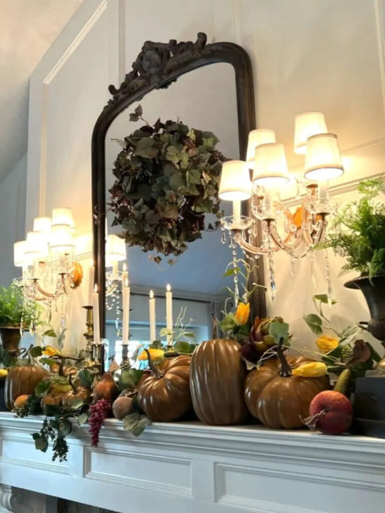 fall mantel with pumpkins and garland, and chandeliers
