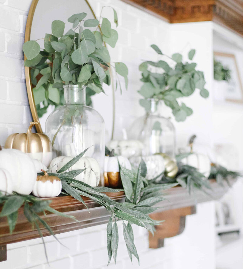 white pumpkins and green faux foliage on rustic fall mantel