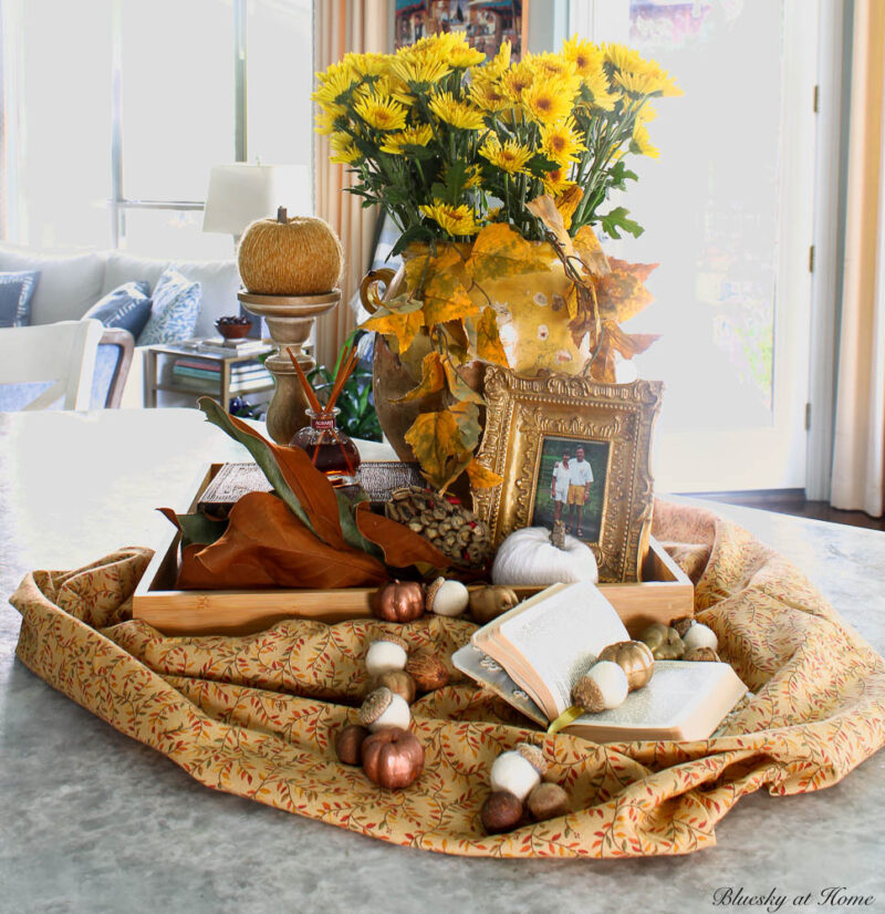 fall vignette in golds, browns, yellows, and oranges with confit pot, fall foliage, books, and sunflowers