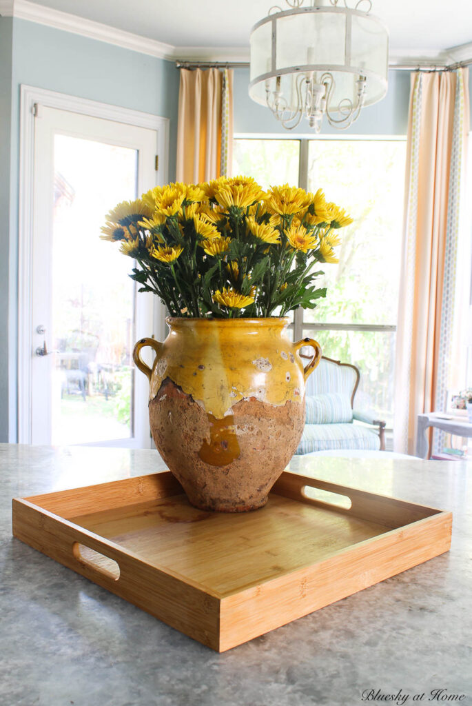 square wood tray with confit pot of yellow flowers