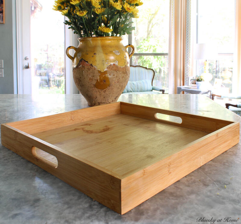 square wood tray with confit pot of yellow flowers