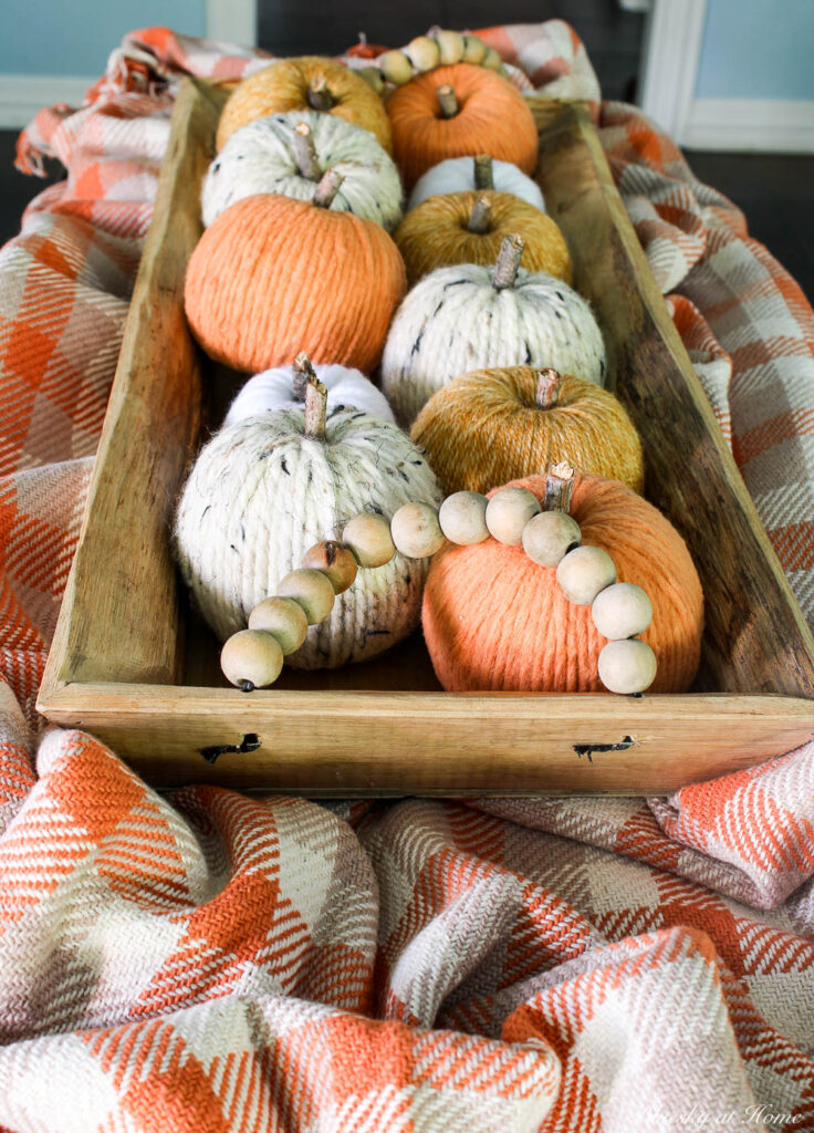 orange, gold, wheat, white yarn pumpkins in wood tray