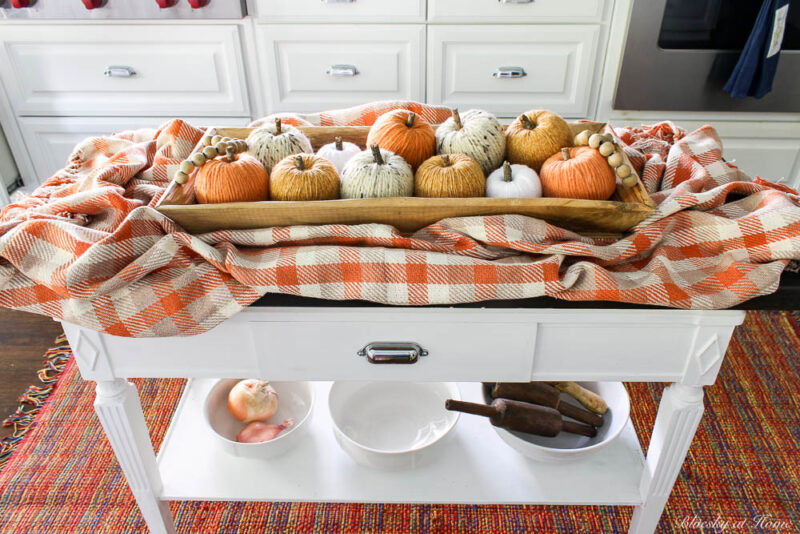 orange, gold, wheat, white yarn pumpkins in wood tray on wood table