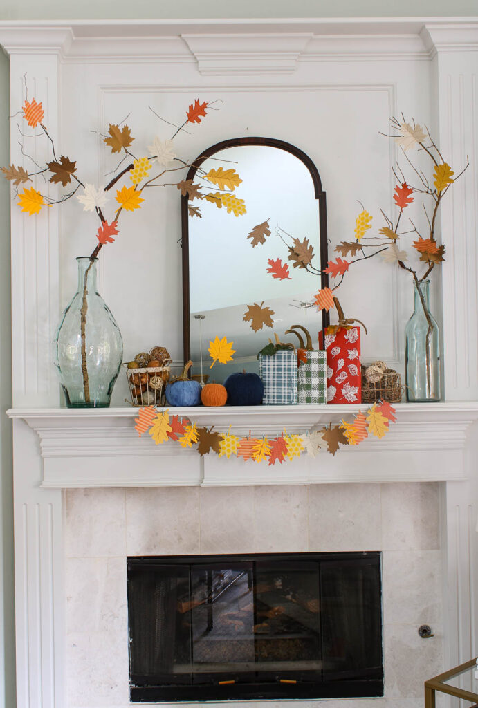 fall mantel with paper leaf garland, tree, and pumpkins