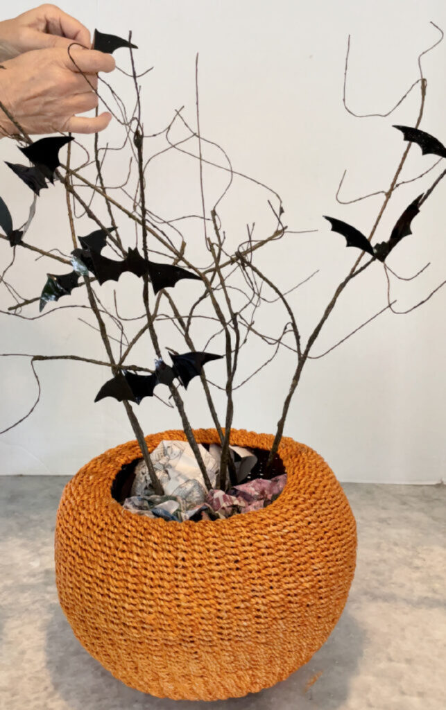 curly twig branches with bat stickers in woven pumpkin basket