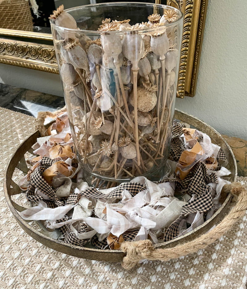 dried poppies in glass vase in a metal tray with rope handles