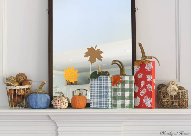 fall mantel with wood block pumpkins in red, green, and blue and pumpkins