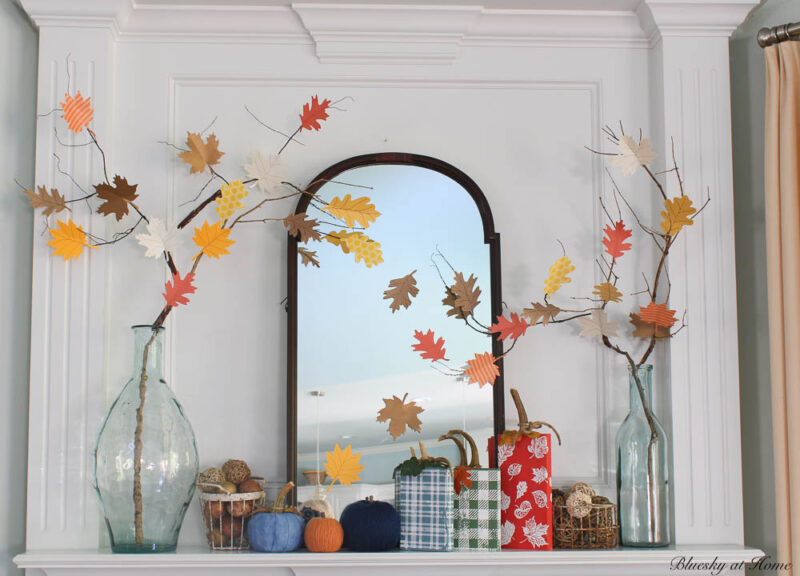 fall mantel with wood and yard pumpkins in red, orange, blue, navy and basket of fall balls