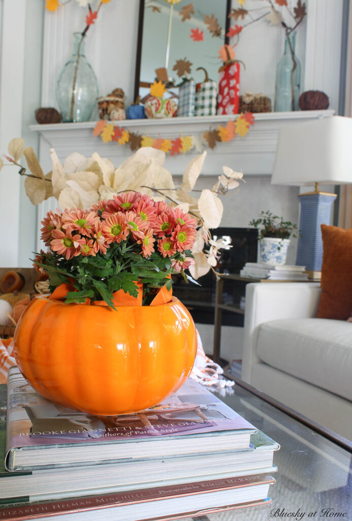 coral chrysanthemums in ceramic orange pumpkin on stack of books