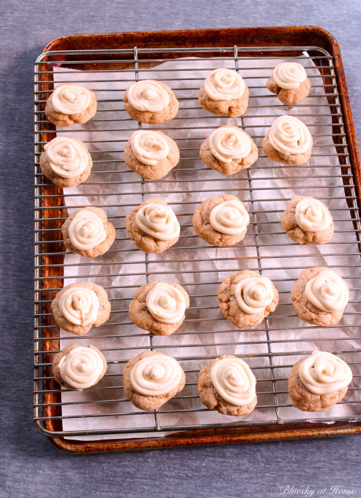 cinnamon roll cookies on cooling rack with frosting