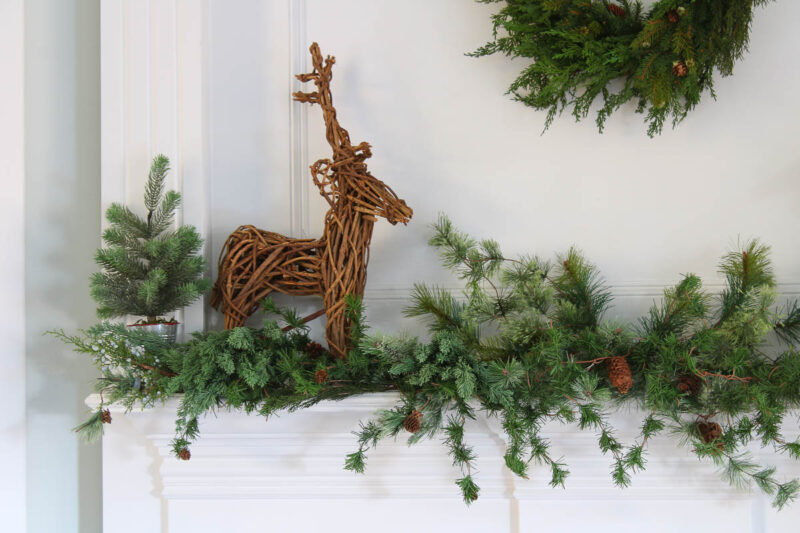 greenery garland on white mantel with twig deer