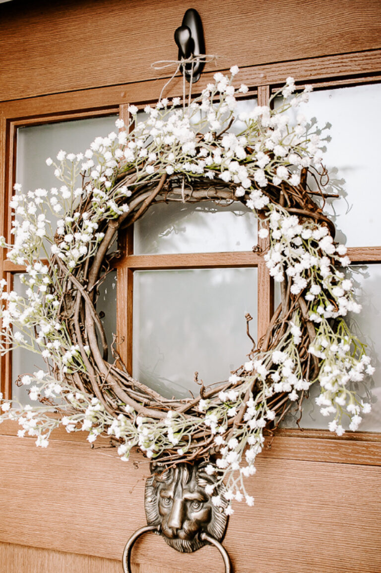 grapevine wreath with white flowers on a front door