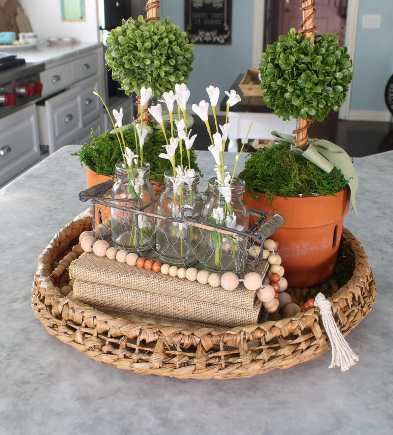 topiaries with burlap books and white flowers in a woven tray