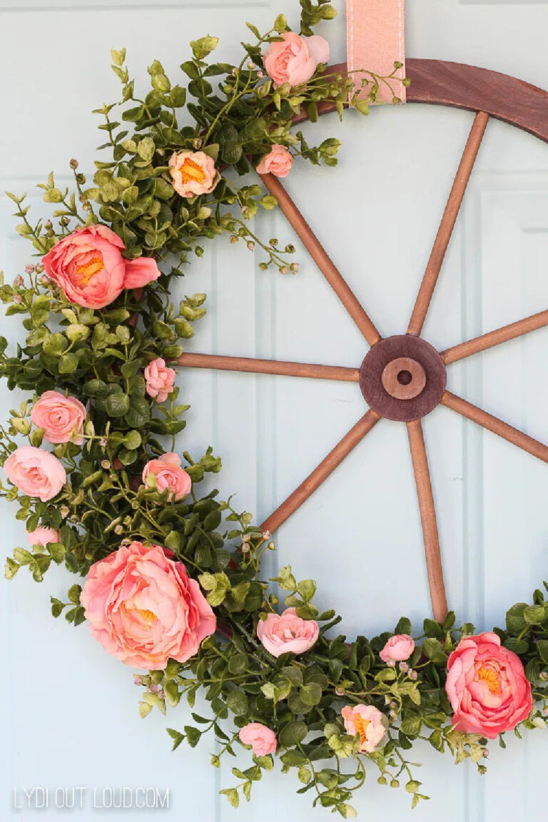spring wreath with orange flowers and boxwood greenery on a wagon wheel