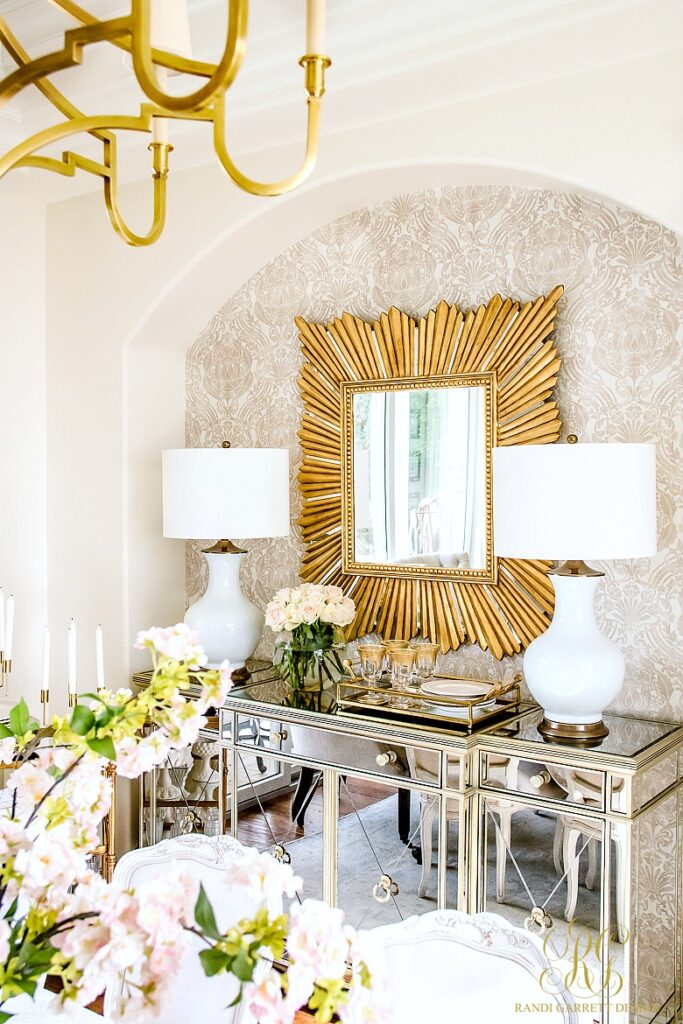 glamourous dining room with gold frame mirror and white lamps