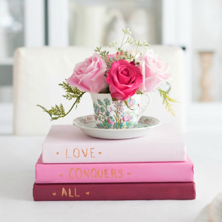 teacup floral flowers sitting on stack of pink books