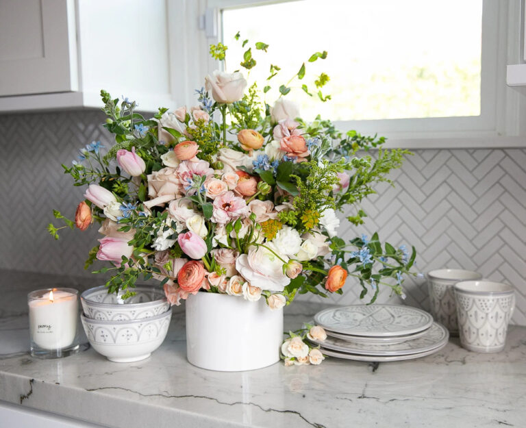 variety of spring flowers in white crock on kitchen counter.