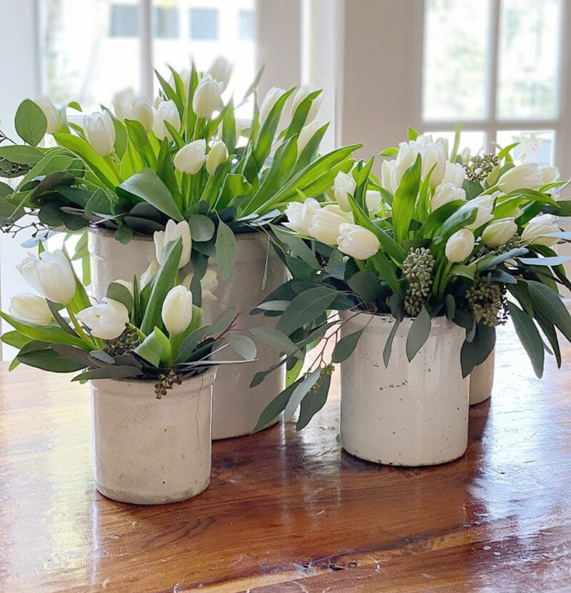 collection of white tulips in white crock pots.