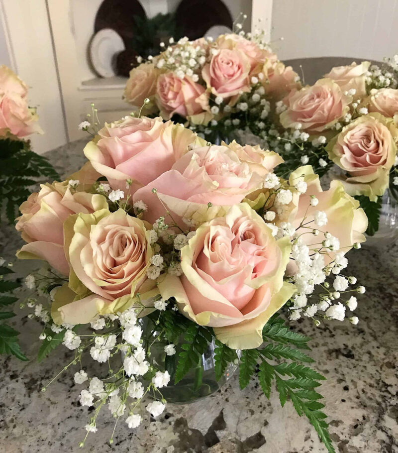 pale pink roses and babies' breath in stemless wine glass