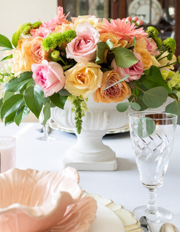 Spring flower centerpiece with pink and orange flowers in white pedestal