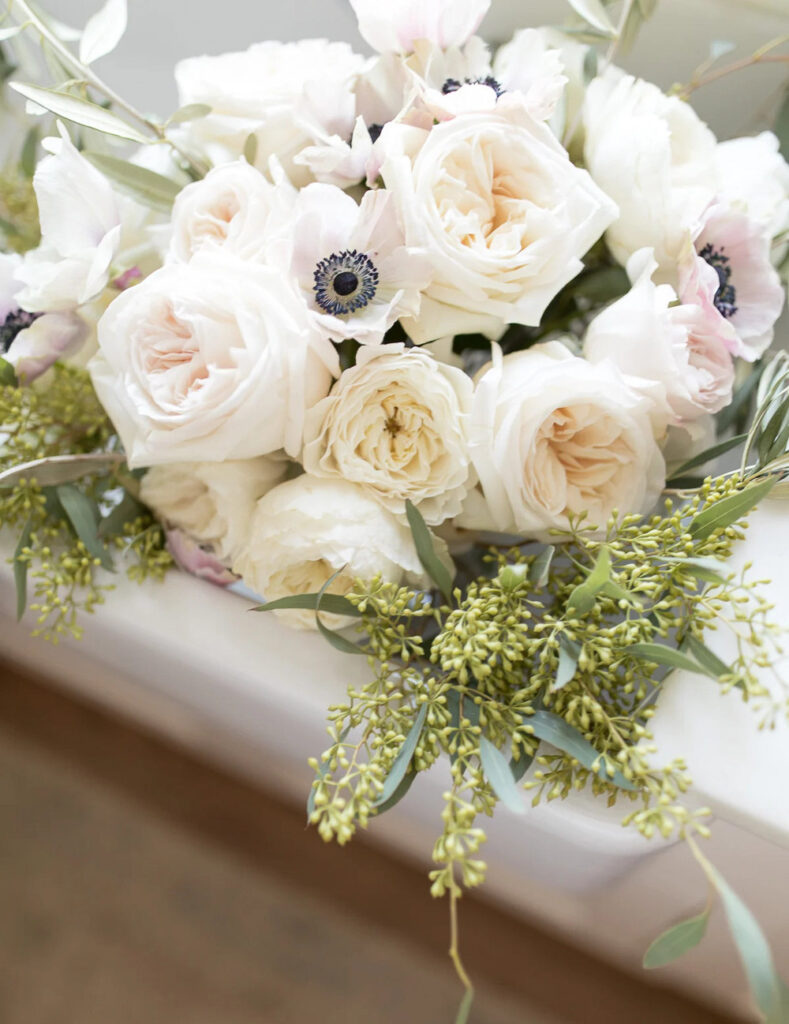 white roses with greenery in white container for spring floral centerpiece.