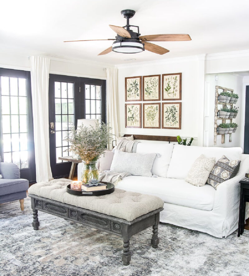 living room with white sofa and upholstered bench and a gallery wall of green art