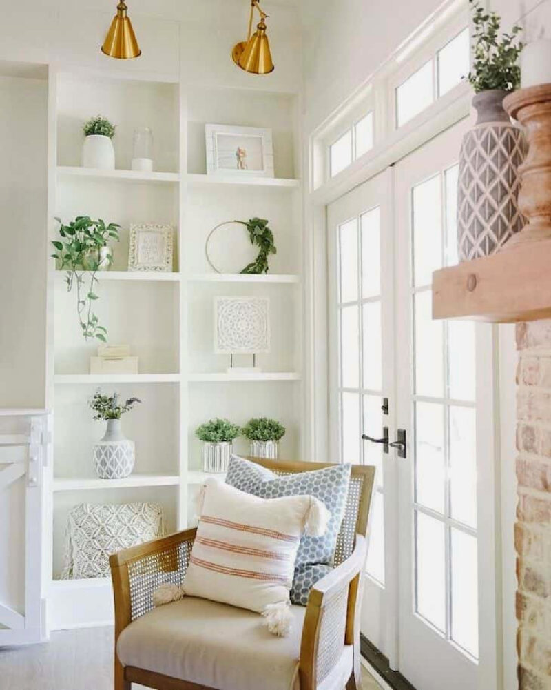 built-in bookcase with a few decorative accessories in neutral colors and a chair in front