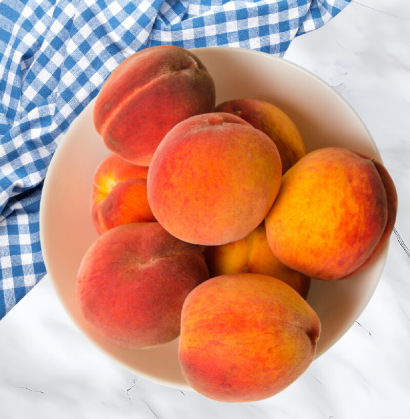 bowl of peaches in white bowl with blue dish cloth