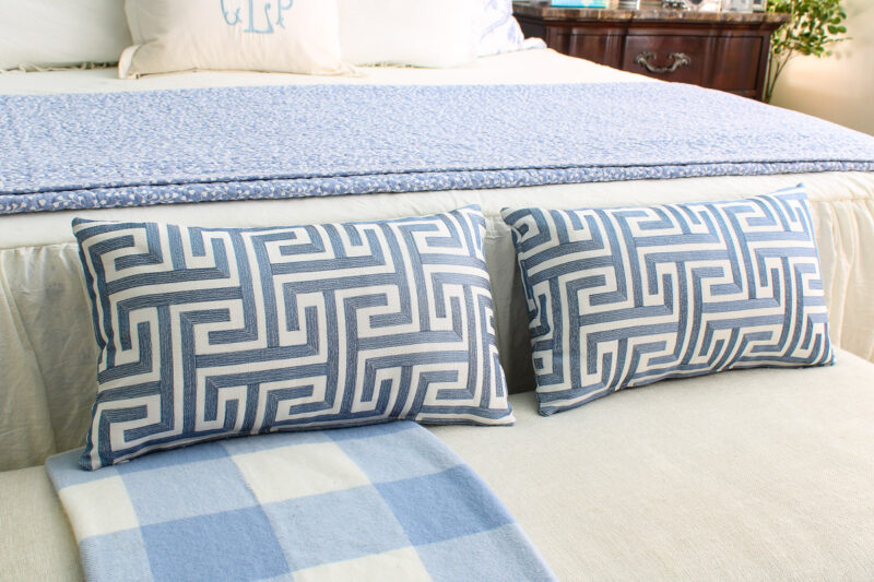 two blue pillows on bench at foot of king bed