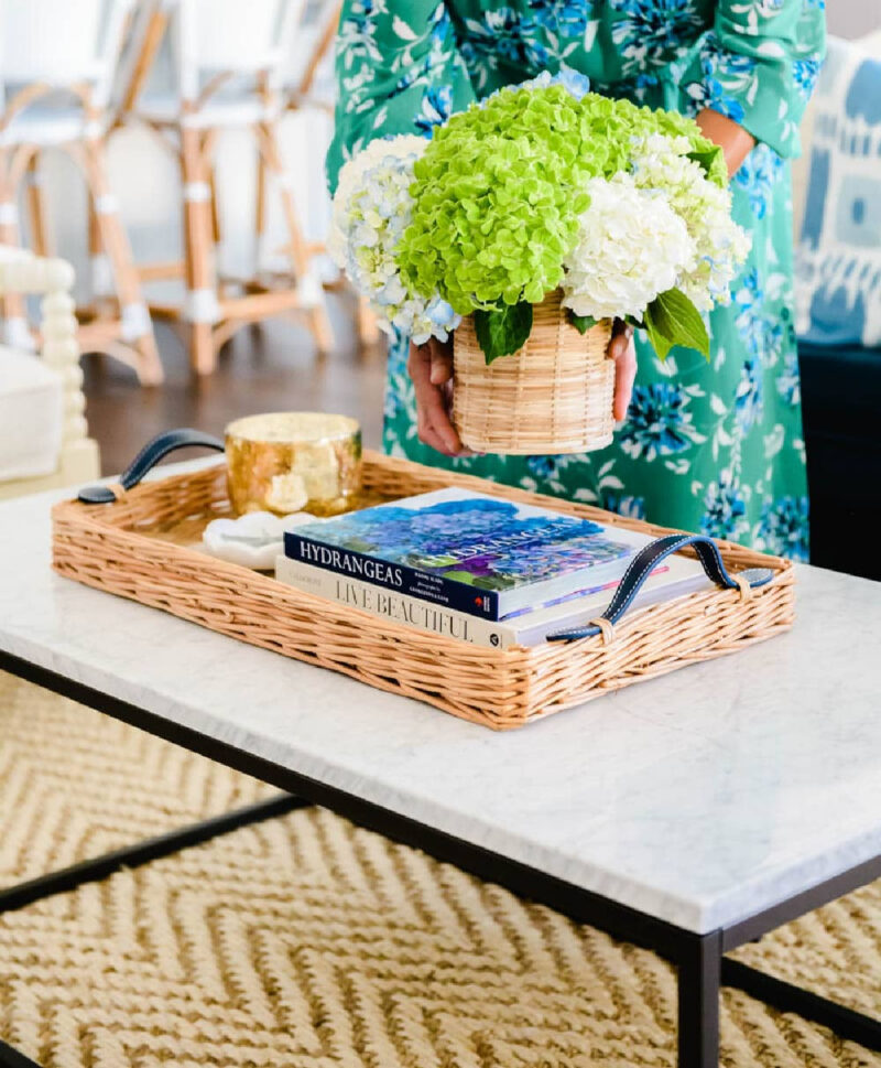 women holding a woven basket of green and white hydrangeas and a woven tray with books