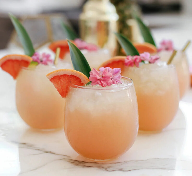 tropical slush cocktail in  glass with slices of fruit