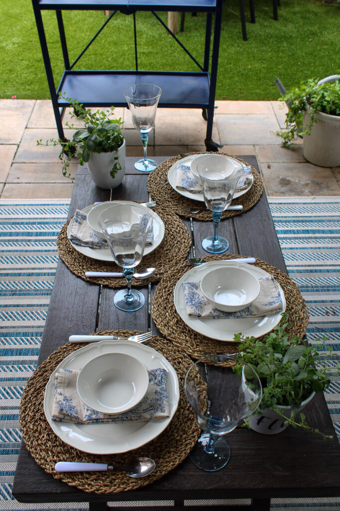 patio table with white dishes with woven placemats