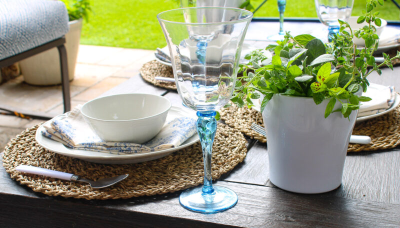 blue-stemmed wine glass on wood table with white dishes