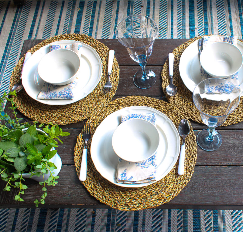 simple place setting with white dishes on woven placemat