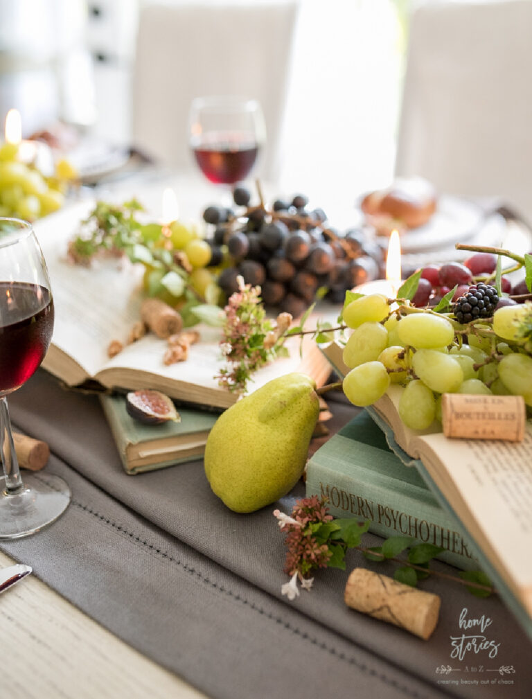 fall table with grapes, pears, and fruit on books on table with wine glasses