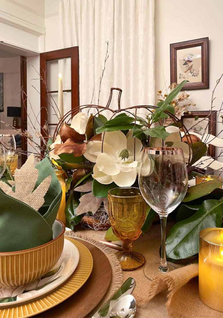 floral fall centerpiece with white flower, green leaves, and burlap leaves