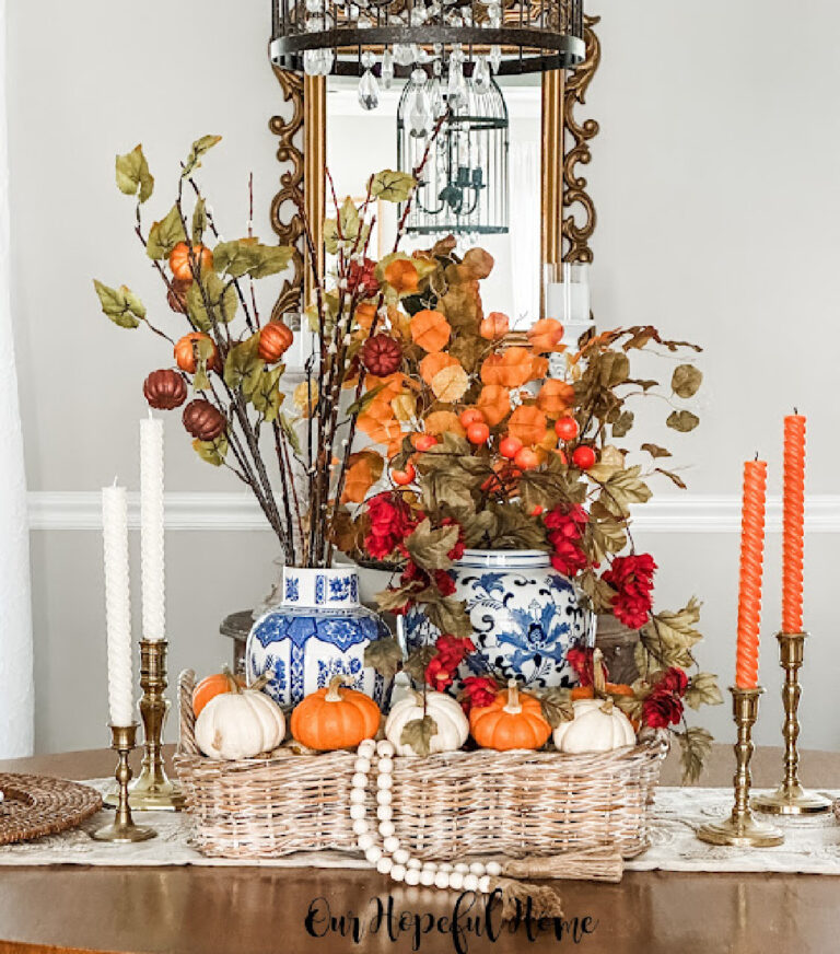 blue chinoiserie vases with orange and white candles and pumpkins in a woven basket