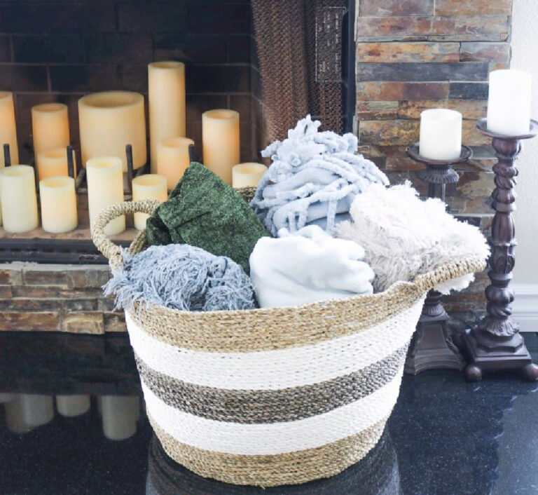 stripe woven basket  filled with rolledup throws in front of fireplace