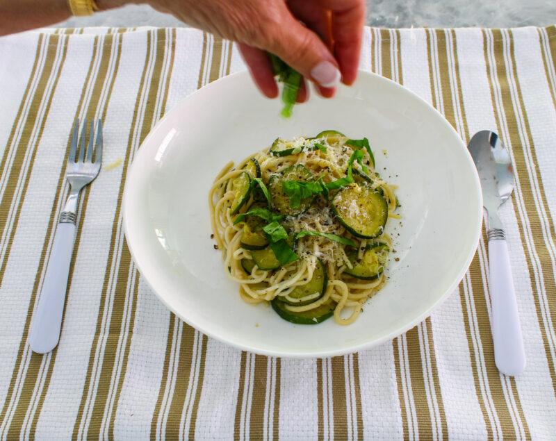 sprinkling zucchini pasta with fresh basil