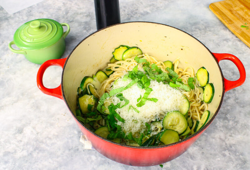 mix of spaghetti and zucchini with grated cheese in a red Dutch oven