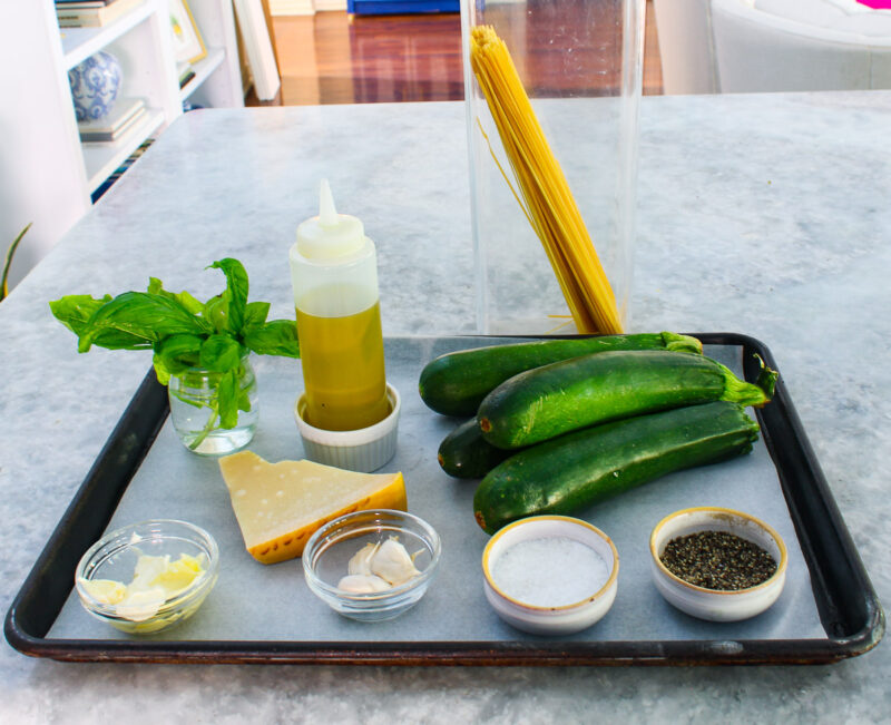 ingredients for zucchini pasta on a sheet pan: zucchini, salt, pepper, garlic cloves, butter, basil, olive oil, spaghetti