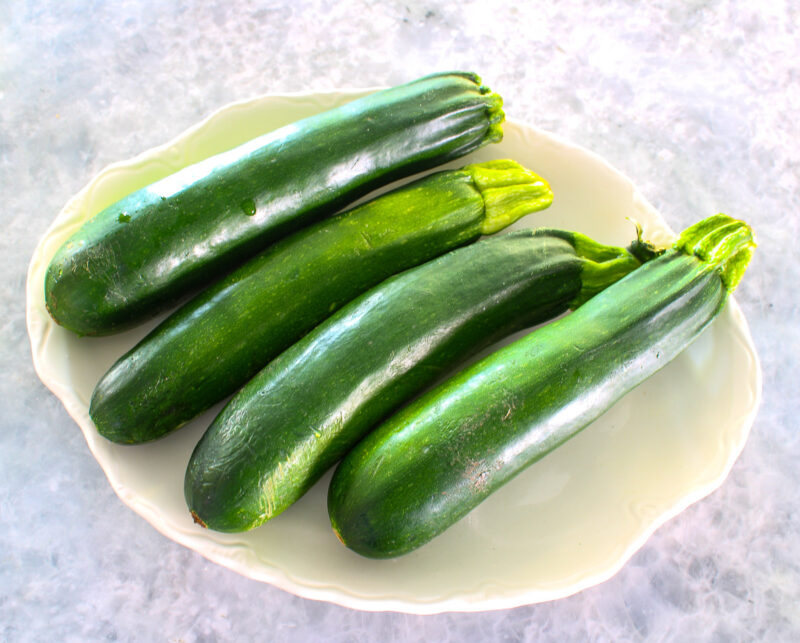 four zucchini on a a white platter