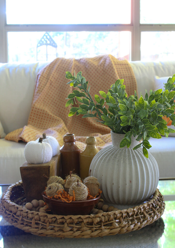 faux acorns in bowl on woven basket on coffee table