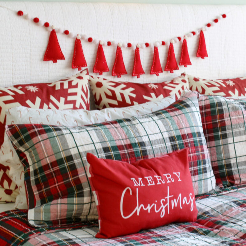 red and plaid bed with pillows and CHristmas tree garland